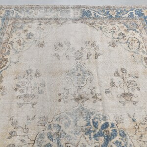 May include: A vintage rug with a light blue and beige floral pattern. The rug has a faded, distressed look and a worn border.