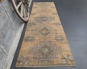 May include: A vintage runner rug with a geometric pattern in shades of beige, brown, and blue. The rug has a distressed look and is perfect for adding a touch of rustic charm to any room.
