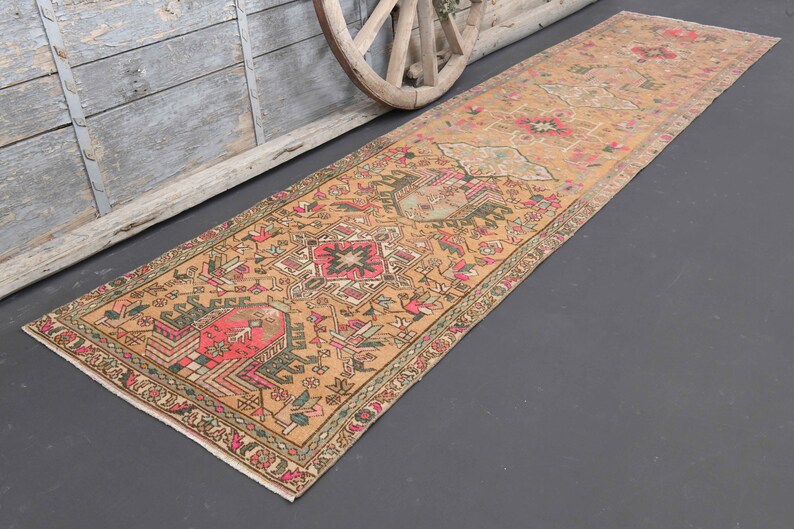 Puede incluir: Una alfombra de pasillo turca vintage con fondo beige y intrincados patrones florales y geom&eacute;tricos en tonos rosa, rojo, verde y azul.