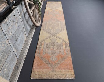 May include: A long, rectangular rug with a geometric pattern in shades of beige, orange, and gray. The rug has a traditional, vintage look.