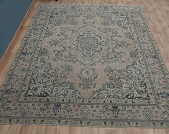 Puede incluir: Una alfombra vintage con fondo rosa claro y un patrón floral detallado en tonos grises y verdes. La alfombra tiene un borde con un patrón repetitivo de pequeñas flores y hojas.