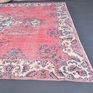K&ouml;nnte beinhalten: Ein vintagefarbener rosa Teppich mit einem floralen Muster in Blaut&ouml;nen, Wei&szlig; und Rosa. Der Teppich hat einen abgenutzten Look und ist perfekt, um jedem Raum einen Hauch von Boho-Stil zu verleihen.