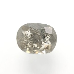 May include: A faceted, oval-shaped, salt and pepper diamond. The gemstone has a mix of gray and white tones with internal inclusions. The diamond is set against a white background, showcasing its natural beauty.