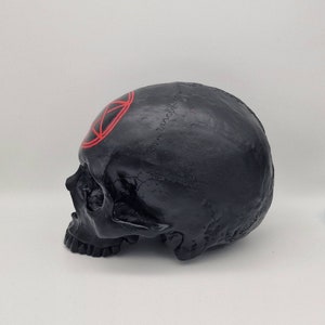 May include: Black skull figurine with a red pentagram painted on the forehead.