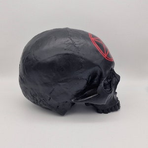 May include: Black skull figurine with a red pentagram painted on the forehead.