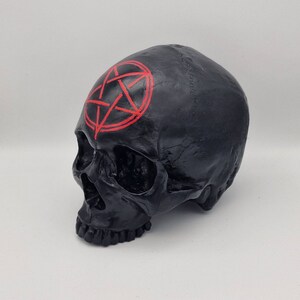 May include: Black skull figurine with a red pentagram painted on the forehead.