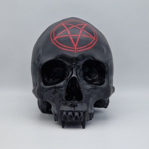 May include: Black skull sculpture with a red pentagram on the forehead.
