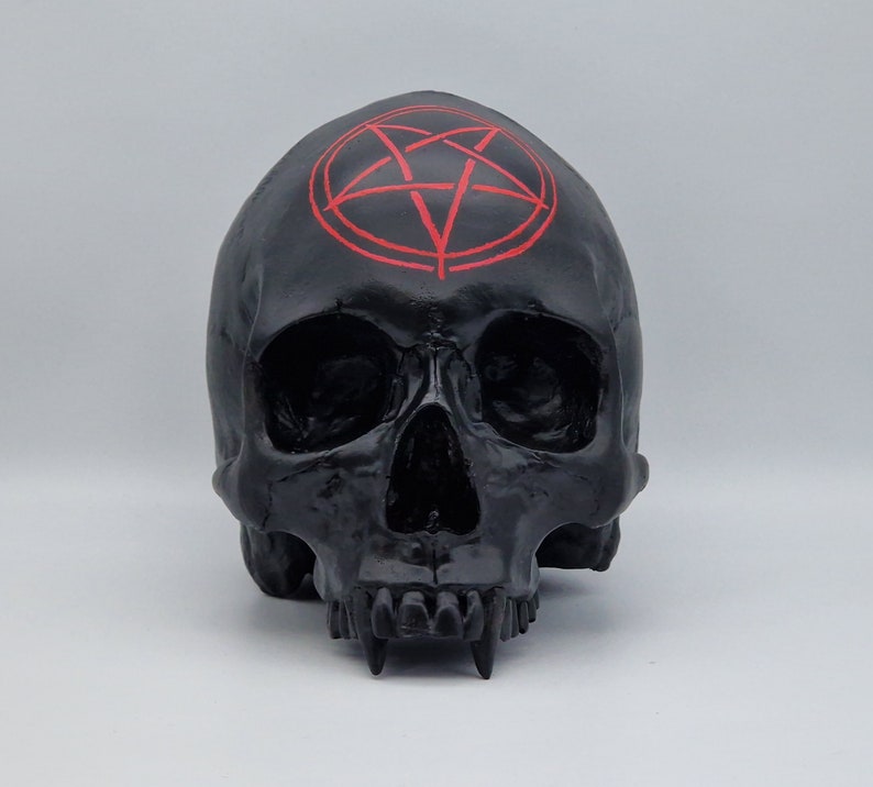 May include: Black skull sculpture with a red pentagram on the forehead.