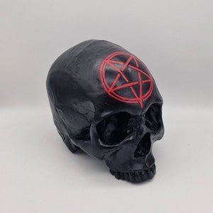 May include: Black skull figurine with a red pentagram painted on the forehead.