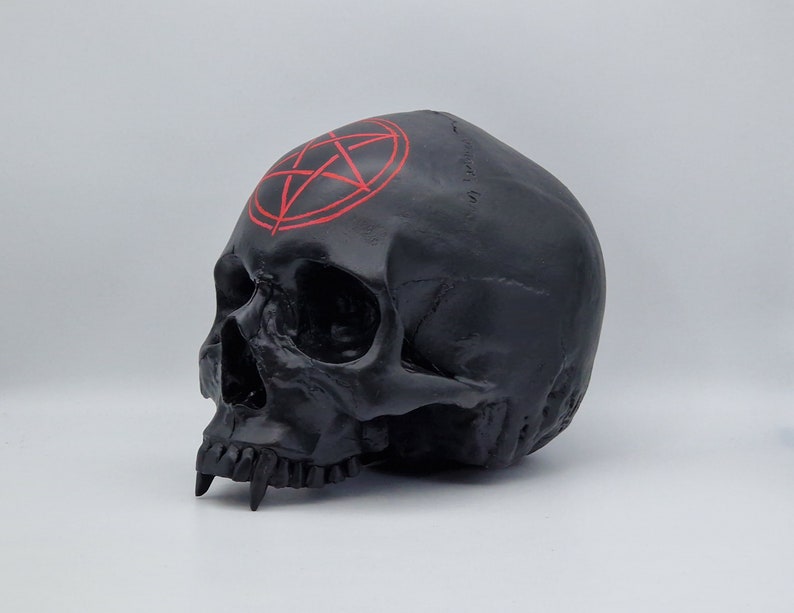 May include: Black skull sculpture with a red pentagram painted on the forehead.