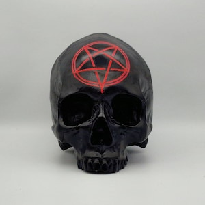 May include: Black skull figurine with a red pentagram painted on the forehead.