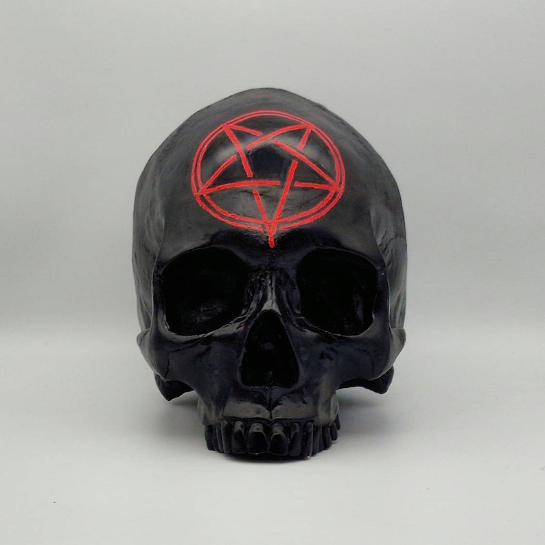 May include: Black skull figurine with a red pentagram painted on the forehead.
