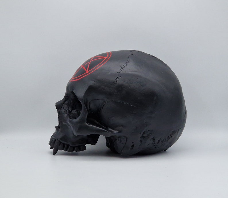 May include: Black skull sculpture with a red pentagram painted on the forehead.