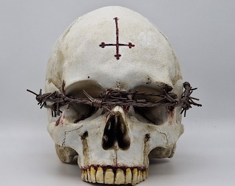 May include: A white skull with a red inverted cross on the forehead and a crown of thorns made of barbed wire.