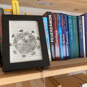 Das Libri-Virus ist ausgebrochen! Linoldruck auf alter Buchseite in schwarzem Rahmen, Buch-Virus Lese-Virus