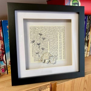 Origami Elefant aus Buchseite und auf Buchseite mit gestempelten Pustenblumen Schirmchen in schwarzem 3D-Rahmen