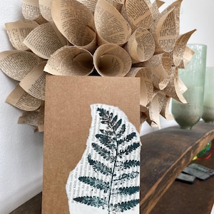 Natürlich verspielte Grußkarte Farn im Naturdruck in dunkelgrün auf Buchseite und Kraftpapier Postkarte