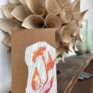 Avec amour : carte de vœux ludique fleurs en imprimé naturel dans des tons rouge et orange sur page de livre et carte postale en papier kraft