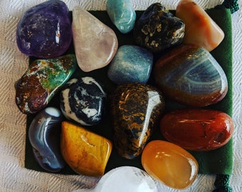 May include: A collection of 14 polished stones in various colors and patterns, including green, brown, blue, white, gray, red, orange, and purple. The stones are arranged on a green felt surface.