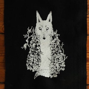 Könnte beinhalten: Schwarzer Stoff-Patch mit einem weißen gestickten Bild eines Wolfes mit einem floralen Design drumherum.