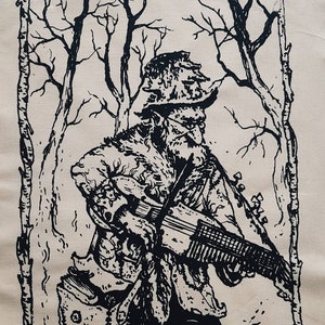 May include: A black and white illustration of a person in a hooded cloak playing a stringed instrument in a woodland setting. The person is holding the instrument in their left hand and has a long beard. The woodland is depicted with bare trees and a simple frame.