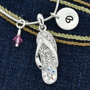 May include: Silver necklace with a crystal-encrusted flip-flop charm, a small pink crystal charm, and a silver charm with the letter "B".