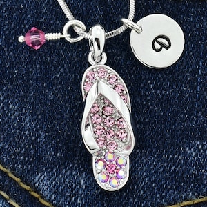 May include: A silver necklace with a pink crystal flip-flop charm and a silver charm with the letter "B" on it.
