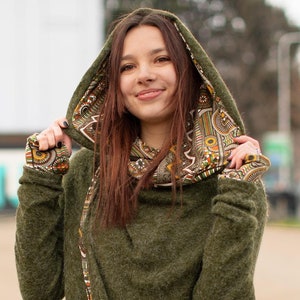 May include: A green hooded sweater with a patterned lining. The sweater has a long, flowing design and a relaxed fit.