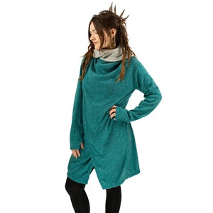 May include: A teal blue long-sleeved sweater with a cowl neck and a relaxed fit. The sweater is made of a soft, comfortable fabric and has a slightly textured surface.