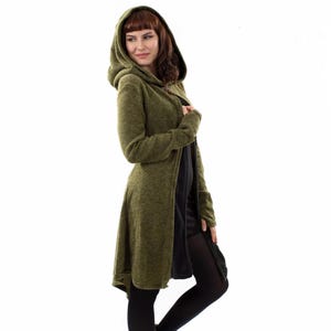 May include: An olive green hooded cardigan with long sleeves and a textured knit finish. The garment features a hood, an open front design, and a slightly longer hemline in the back, worn over a plain black dress and black tights.