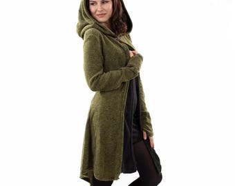May include: An olive green hooded cardigan with long sleeves and a textured knit finish. The garment features a hood, an open front design, and a slightly longer hemline in the back, worn over a plain black dress and black tights.