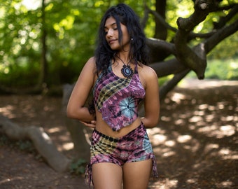May include: A tie-dye halter top and matching shorts set in shades of pink, purple, yellow, and blue. The shorts have drawstring details on the sides. A black pendant necklace with a circular design is also visible.