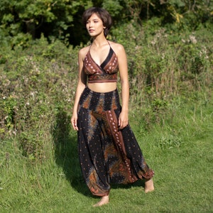 Könnte beinhalten: Eine Frau trägt ein schwarzes und braunes gemustertes Crop-Top und eine passende Hose. Das Outfit hat einen Boho-Stil.