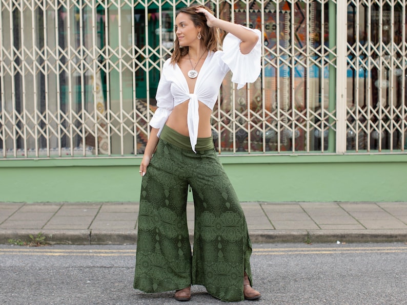May include: A woman wearing a white crop top with a tie front and a green patterned wide-leg pant.