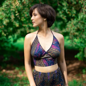 Puede incluir: Una mujer con un top halter y una falda a juego con estampado floral. El top es un top corto y la falda es una falda de cintura alta. La mujer está de pie en un entorno boscoso.