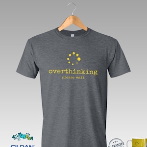 May include: A dark heather grey t-shirt with a yellow graphic of a loading circle and the text "overthinking please wait".