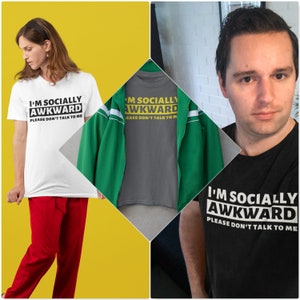 Puede incluir: Tres camisetas con el texto "I'm Socially Awkward Please Don't Talk To Me" en letras amarillas sobre fondo negro. Las camisetas son blanca, gris y negra. La camiseta blanca la lleva puesta una persona. La camiseta gris la lleva puesta una persona. La camiseta negra la lleva puesta una persona.