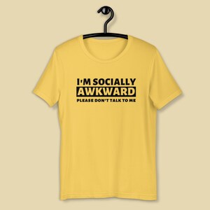 Puede incluir: Camiseta amarilla de manga corta con texto negro que dice "I'm Socially Awkward Please Don't Talk To Me."