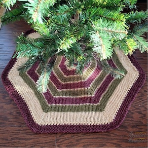 May include: A crocheted Christmas tree skirt in burgundy, beige, and green stripes. The skirt is shaped like a hexagon and has a textured, knitted design.