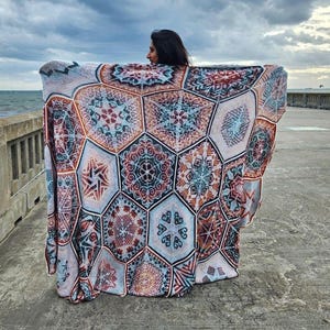 May include: A large crocheted blanket with a geometric pattern in shades of blue, brown, white, and orange. The blanket is made up of multiple hexagonal panels, each with a different design.