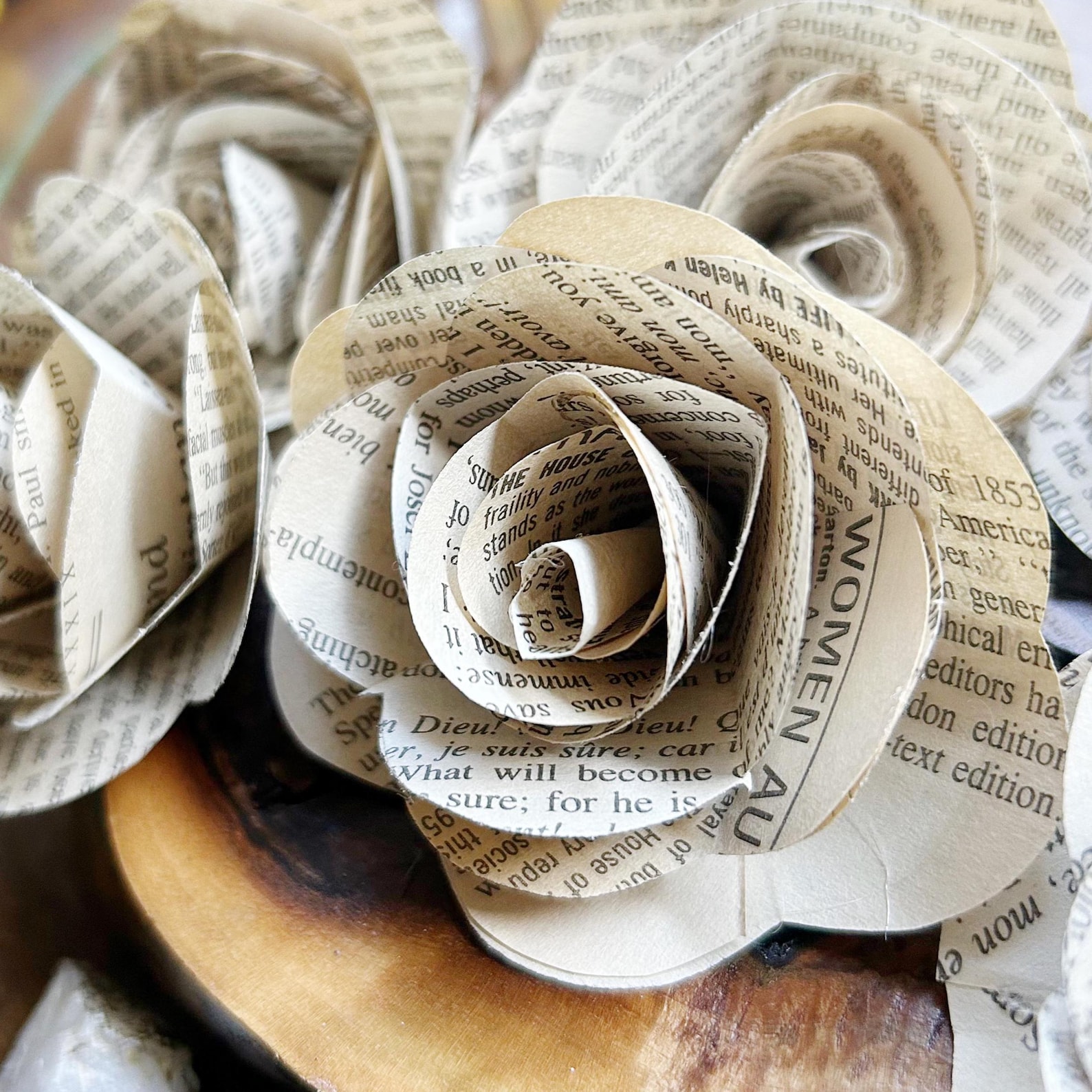 Close-up of intricately crafted paper roses made from book pages. The text on the petals is visible.