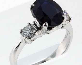 May include: A silver ring with a large oval-shaped blue sapphire gemstone and two smaller round diamonds on the band.