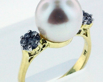 May include: A gold ring with a large white pearl and two smaller diamond accents.