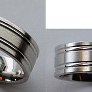 May include: A silver wedding band with three grooves around the band.