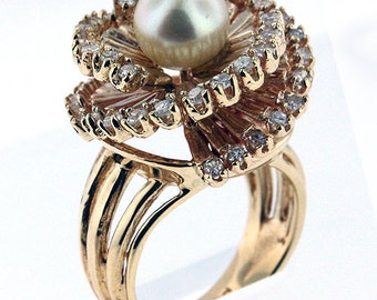 May include: A gold ring with a large pearl and a flower design made of small diamonds.