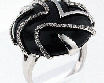 May include: A silver ring with a black onyx stone set in a swirl design. The ring is accented with small diamonds.