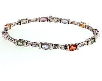 May include: A silver bracelet featuring a series of oval-cut gemstones in various colors, including pink, green, orange, and blue. The bracelet has a delicate design with small, sparkling accents and a secure clasp.
