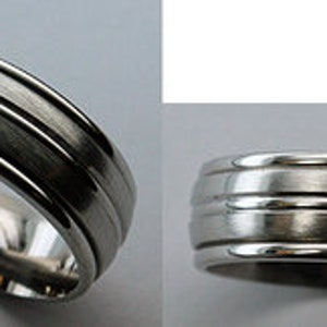 May include: A silver wedding band with a brushed finish and three grooves around the band.