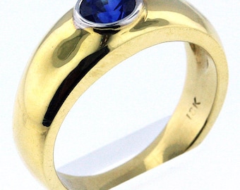 May include: A gold band ring with a blue sapphire gemstone set in a white metal bezel. The ring is marked "14K" on the inside.