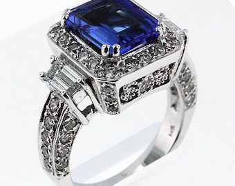 May include: A silver ring with a large, emerald-cut blue gemstone surrounded by smaller diamonds. The band is also set with diamonds.